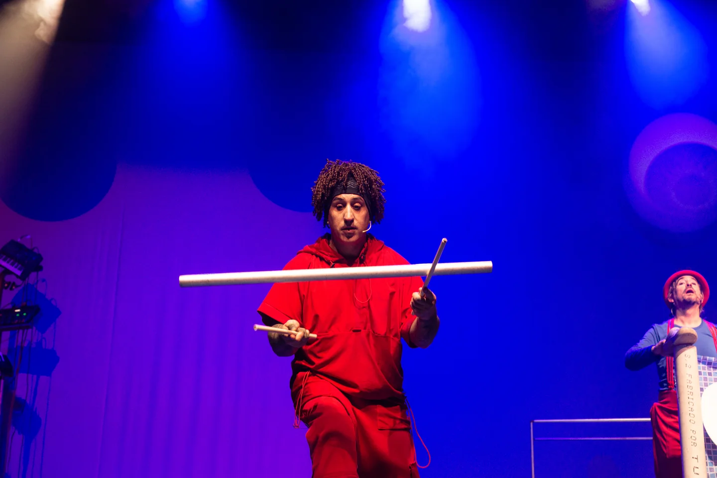 Intérprete con vestuario rojo manipulando objetos bajo luz azul en un escenario