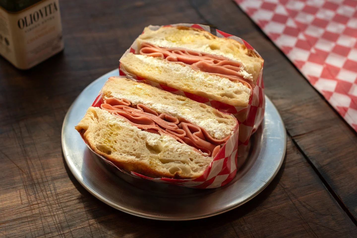 Dos mitades de un sándwich sobre papel rojo y blanco en una mesa oscura