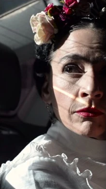Video vertical de una intérprete con flores en el pelo recorriendo espacios urbanos y cierre promocional de Frida