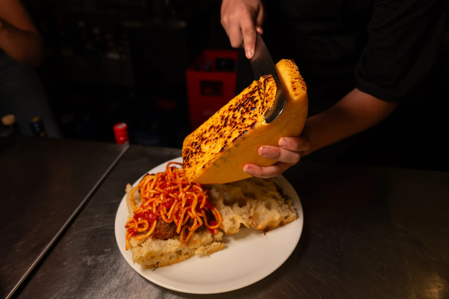 Manos colocando pan tostado sobre una preparación servida en un plato