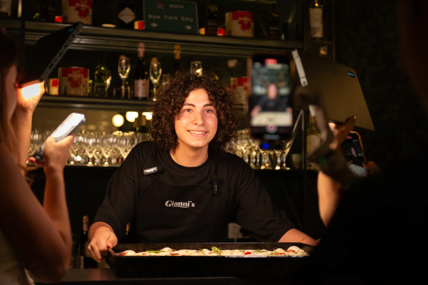 Persona sosteniendo una bandeja de comida ante teléfonos y luces de grabación